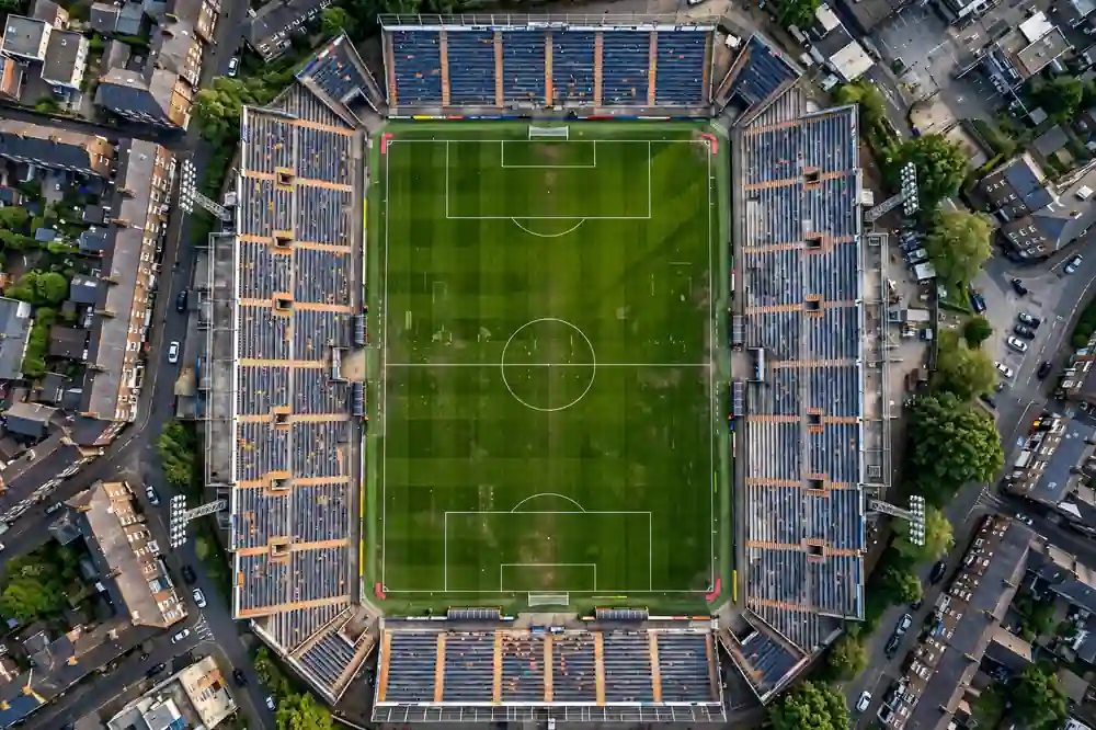 Aerial view of a compact narrow stadium pitch with steep stands